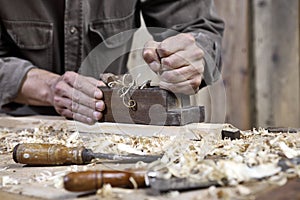 Hands of carpenter plane on workbench in carpentry