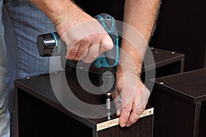 Hands carpenter with screwdriver, tighten in drawers of ch