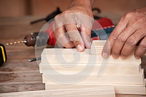 Hands of a carpenter taking measurement of a wooden plank