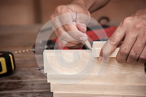 Hands of a carpenter taking measurement of a wooden plank