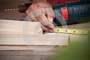 Hands of a carpenter taking measurement of a wooden plank ,Wood working concept