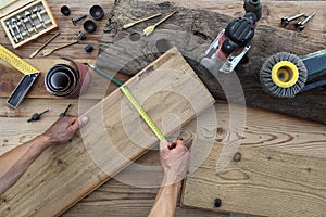 hands carpenter work the wood, measuring with tape meter old rustic wooden boards, top view with tools on background