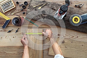 hands carpenter work the wood, measuring with tape meter old rustic wooden boards, top view with tools on background