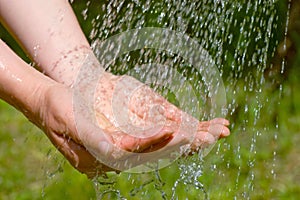 Hands catching clean falling water close up