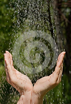 Hands catching clean falling water close up