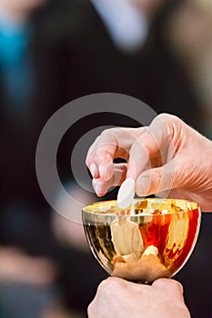 Hands of a catholic priest with chalice and host at Communion