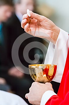 Hands of a catholic priest with chalice and host at Communion