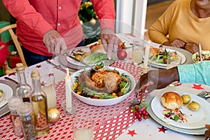 Hands of cauasian senior man cutting chicken at christmas table photo