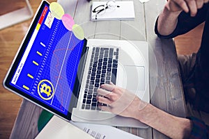Hands of caucasian businessman sitting at desk using laptop with statistical data on screen photo