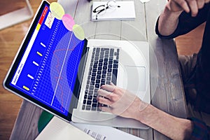 Hands of caucasian businessman sitting at desk using laptop with statistical data on screen photo