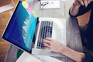 Hands of caucasian businessman sitting at desk, using laptop with statistical data on screen photo