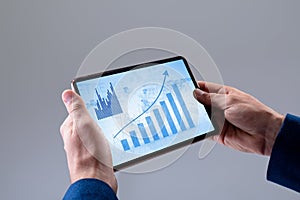 Hands of caucasian businessman using tablet, with graphs on blue interface screen