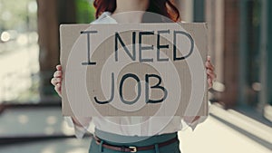 Hands of the caucasian businesswoman holding poster cardboard with need job jobless message, crisis text job showing