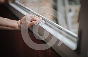 Hands of a Caucasian man cleans the window frame.