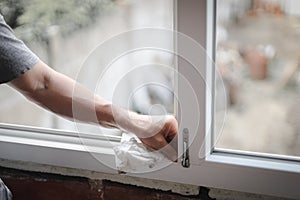 Hands of a Caucasian man cleans the window frame.