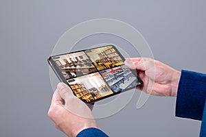 Hands of caucasian man holding tablet with view of library from security cameras on screen