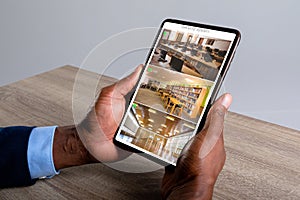 Hands of caucasian man holding tablet with view from security cameras at library on screen