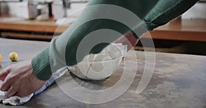 Hands of caucasian man uncovering bread dough in kitchen, slow motion