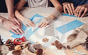 Hands of a caucasian mother and her daughter are cutting paper snowflakes with scissors. Handmade, christmas decorations, family