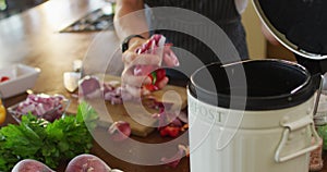 Hands of caucasian pregnant woman wearing apron, putting peels into trash bin