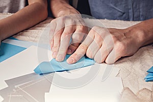 Hands of a caucasian teenager cutting paper snowflakes with scissors. Handmade, christmas decorations, family winter activity.