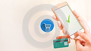 Hands with a cellphone with an OK and icons of a cart and credits cards. Relative to shopping online. Background, collage or