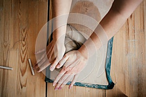 Hands of a ceramist roll out soft, raw white clay