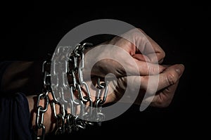 Hands chained in chains isolated on black background