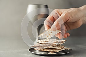 Hands with chalice and communion matzo bread, wooden cross on grey background. Christian communion for reminder of Jesus sacrifice