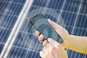 Hands checking solar power generation in a smartphone app.