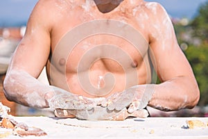 Hands of chef cook working with dough and flour, muscular torso on background. Bakery concept. Hands of muscular baker