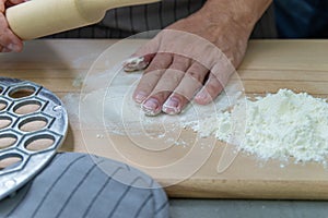 The hands of the chef knead the dough on a wooden table