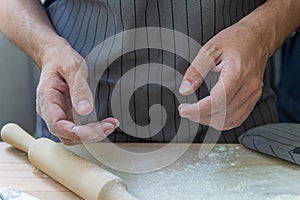 The hands of the chef knead the dough on a wooden table