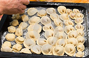 The hands of the chef placed the dumplings on a baking sheet. Handmade homemade Russian Siberian dumplings.