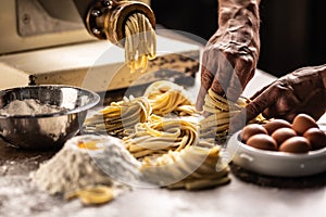 Hands of a chef twisting fettuccine pasta into nests after making a fresh dough from the ingredients