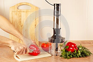 Hands chefs cut red bellpepper on kitchen table