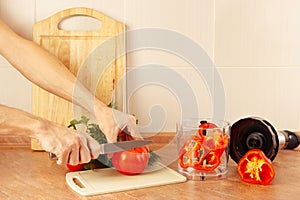 Hands chefs cut red tomato on kitchen table