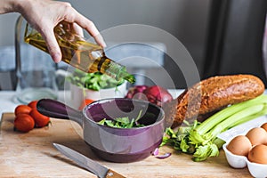 Hands of chefs prepare a salad of fresh and healthy ingredients, vegetables and olive oil in the kitchen