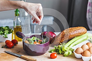 Hands of chefs prepare a salad of fresh and healthy ingredients, vegetables and olive oil in the kitchen