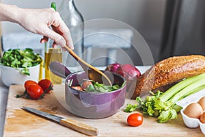 Hands of chefs prepare a salad of fresh and healthy ingredients, vegetables and olive oil in the kitchen