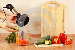 Hands chefs put chopped cucumber in blender