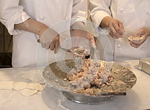 Hands of chefs stuffing meat for the grilled rice dumplings at Chinatown in Kobe in Japan