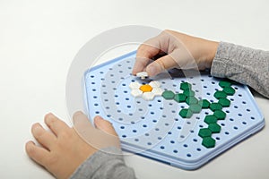 Child compiles mosaic on white background. photo