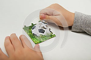 Hands of a child compile a puzzle with a soccer ball photo