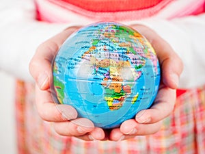 Hands of a child holding globe