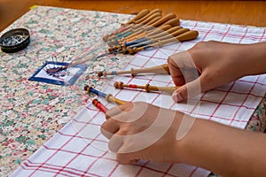 Hands of child making bobbin lace. Colorful lace threads