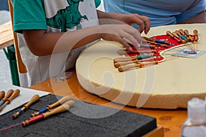 Hands of child making bobbin lace. Colorful lace threads. Skill