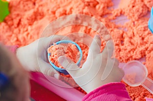 The hands of a child playing with kinetic sand