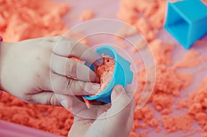 The hands of a child playing with kinetic sand