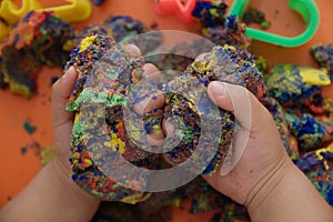 Hands of child playing multicolored kinetic sand. children activity game toy for model forming craft and sculpture art